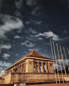 an old building with many flags flying in the air next to it at night time