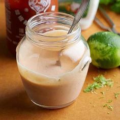 a jar filled with liquid sitting on top of a table next to some limes