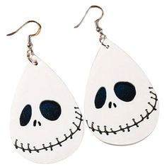 two white tear shaped earrings with black eyes and skeleton faces on them, one is hanging from