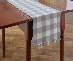 a plaid table runner on top of a wooden dining room table with wood leg legs