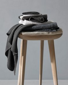 a stack of folded clothes sitting on top of a stool