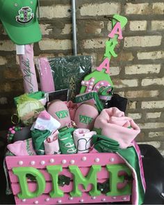 a pink and green birthday gift basket sitting on top of a black cart next to a brick wall