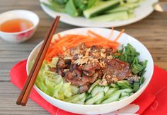 a bowl filled with meat and veggies next to chopsticks on a table