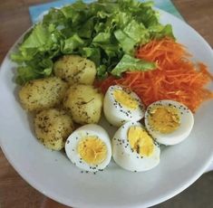 a white plate topped with hard boiled eggs, carrots and lettuce