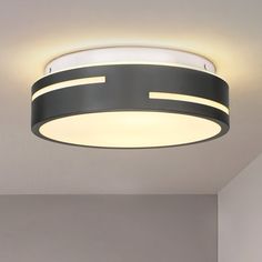 a circular light fixture in a room with white walls and flooring on the ceiling