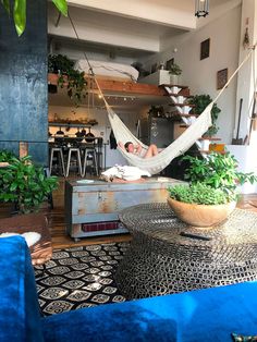 a man laying in a hammock on top of a couch next to a table