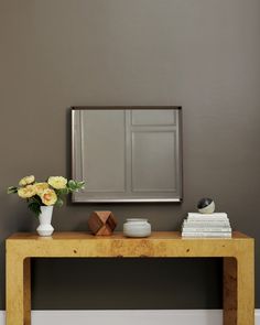 a wooden table with flowers and a mirror on the wall