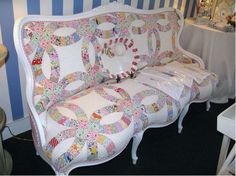 a couch made out of quilts on display in a room with blue and white striped walls