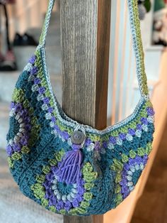 a crocheted purse hanging on a wooden post in front of a staircase way