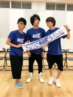 three young men standing next to each other holding up a large piece of paper in front of them