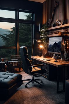 an office with a desk, chair and large window overlooking the mountains at night time