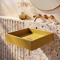 a yellow sink sitting on top of a counter next to a mirror and wall mounted faucet