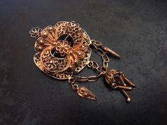 "This handsome, flickering brooch features detailed filigree and cannetille work. The brooch is quite dimensional with raised and dangling ornament. It was probably made in Portugal or Spain. The security clasp works just fine. The brooch is in good shape with some surface wear to the gilding. It is 6.7cm (2 5/8\")long X 3.2cm (1 1/4\")wide. It weighs 10g." Ornate Filigree Jewelry For Evening, Elegant Gold Filigree Brooches, Ornate Wedding Brooch With Intricate Design, Ornate Wedding Brooches With Intricate Design, Antique Pendant Brooch With Intricate Design, Antique Yellow Gold Filigree Brooches, Antique Brooch With Intricate Pendant Design, Victorian Gold Pendant Brooches, Victorian Gold Brooch With Intricate Design