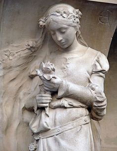 the statue is holding a flower in her hands