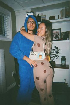 a man and woman dressed up as sesame street characters posing for a photo with cookie monster