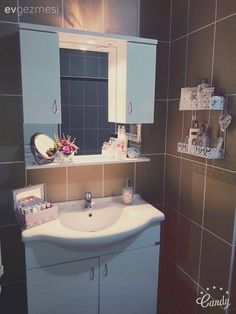 a white sink sitting under a bathroom mirror next to a wall mounted medicine cabinet and towel dispenser