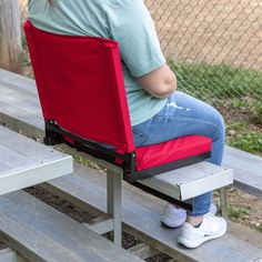 a woman sitting in a red chair on top of a wooden bench