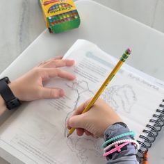 a child's hands holding a pencil and drawing on paper