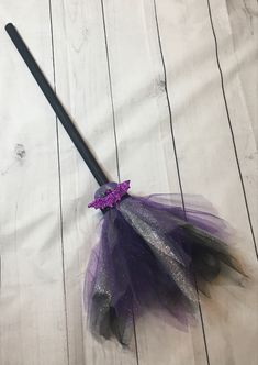 a purple and silver tutule with a black wand on it sitting on a white surface