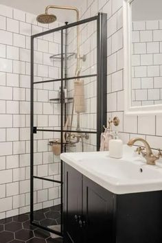 A black-and-white bathroom with hexagon floor tiles, while wall tiles and brass fixtures