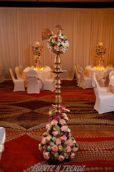 an elaborately decorated floor lamp with flowers on it in the middle of a banquet room