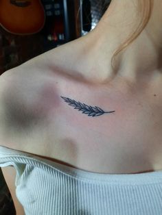 a woman with a tattoo on her shoulder has a feather in the middle of her chest