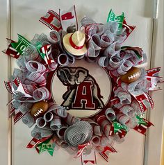 a wreath made out of ribbon and footballs on the front door with a hat