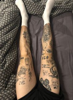 a person laying in bed with tattoos on their arms and legs, both covered by blankets