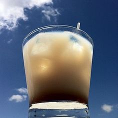 a tall glass filled with liquid on top of a beach