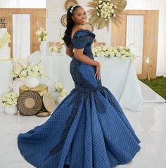 a woman standing in front of a table wearing a blue dress