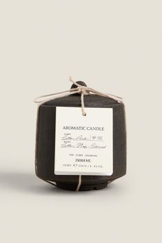 an aroma candle is wrapped in twine and sits on a white surface with a brown string around it