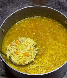 a pot filled with noodles and carrots on top of a table