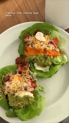 two lettuce wraps filled with meat, cheese and sauce on a white plate