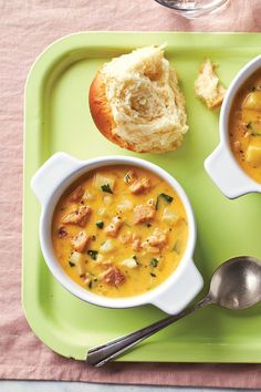 two bowls of soup and bread on a green tray