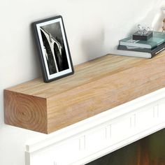 a white fireplace with a wooden mantle and books on it