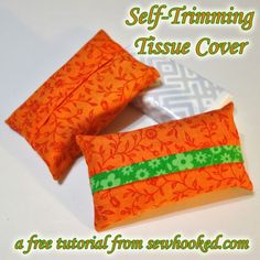 two orange and green pillows sitting on top of a white table next to each other