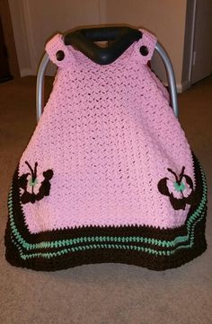 a pink crocheted blanket sitting on top of a metal chair next to a door