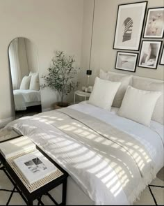 a bedroom with white bedding and pictures on the wall