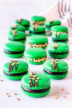 there are many green macaroons with gold decorations on them and the words guinness macaroons written in black