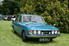 an old blue car is parked in the grass