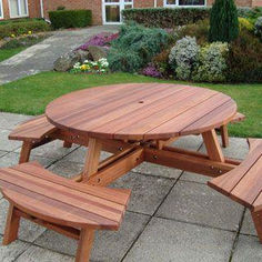 a wooden picnic table and benches in front of a house