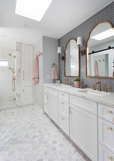 a bathroom with white cabinets and gold accents