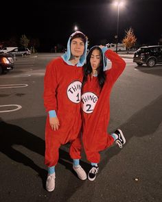 two people dressed up in costumes posing for a photo at the parking lot with their hands on their head