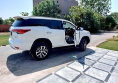 a white suv parked in front of a building with its door open and the driver's seat up