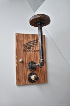 a wall mounted light fixture on the side of a white wall with wood and metal fittings