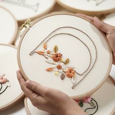 a person is holding up some embroiderys with flowers on them and the letters d are made out of wood