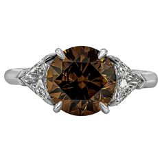 A unique diamond stone engagement ring, showcasing a 3.04 carats round brilliant cut diamond certified by GIA as Fancy Dark Orangey Brown color and SI2 clarity, set on a four claw prong basket. Flanked by two gorgeous trillion cut diamonds weighing 0.74 carat total. Set on a chic knife-edge platinum shank. Size 6.5 US, resizable upon request. Roman Malakov is a custom house, specializing in creating anything you can imagine. If you would like to receive a special quote on a custom piece, please Diamond Cocktail Rings, Three Stone Engagement, Three Stone Engagement Rings, Unique Diamonds, Brown Diamond, Orange Brown, Gold Platinum, Jewelry Rings Engagement, Round Brilliant Cut Diamond