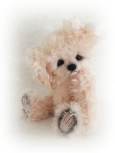 a small teddy bear with black eyes and pink fur on it's legs, sitting in front of a white background