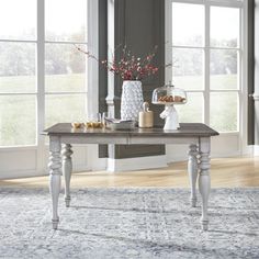 a dining room table in front of large windows with an area rug on the floor