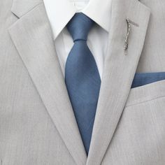 a man in a suit with a blue tie and pin on his lapel collar